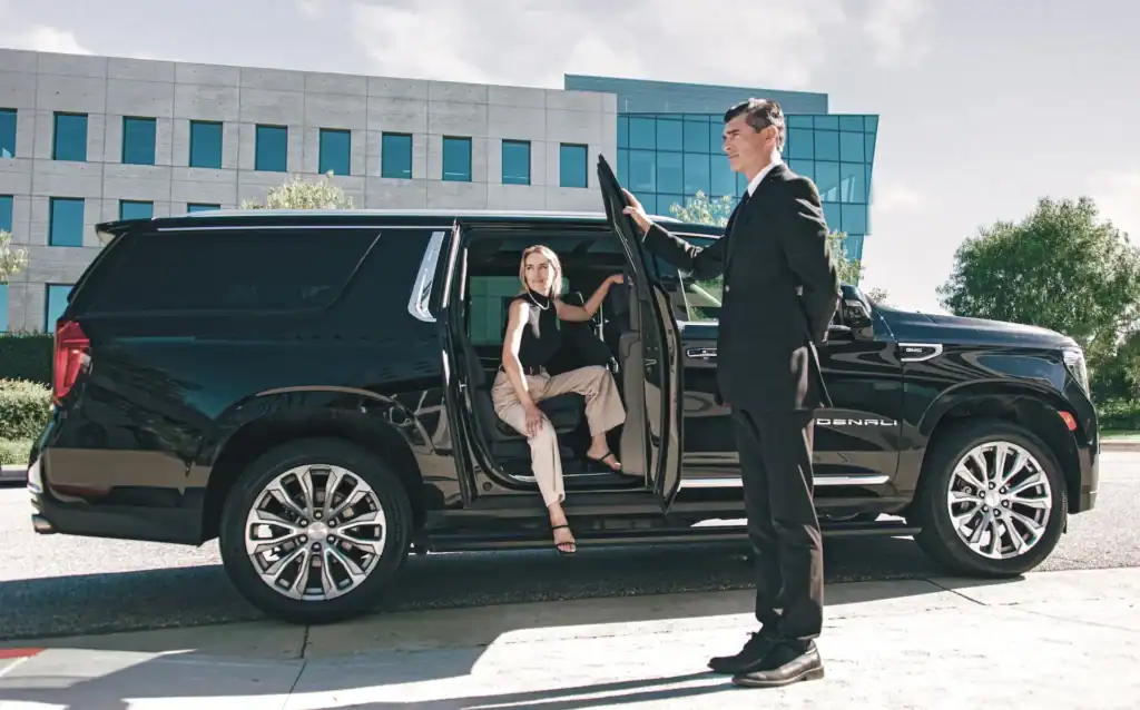 Professional chauffeur assisting a passenger into a luxury black SUV in Orange County.