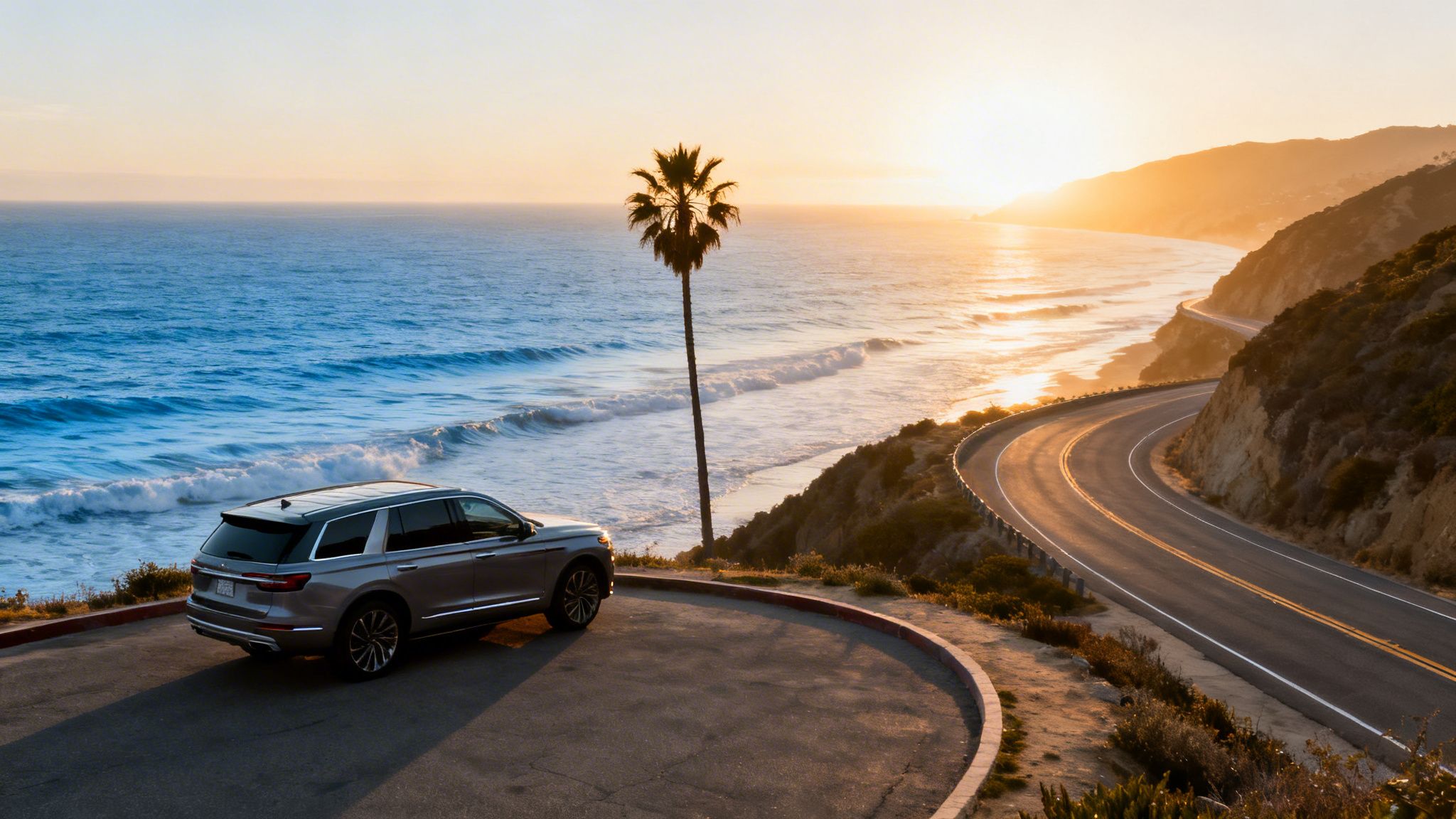 Luxury SUV parked overlooking a beautiful ocean sunset with a palm tree and winding coastal highway.