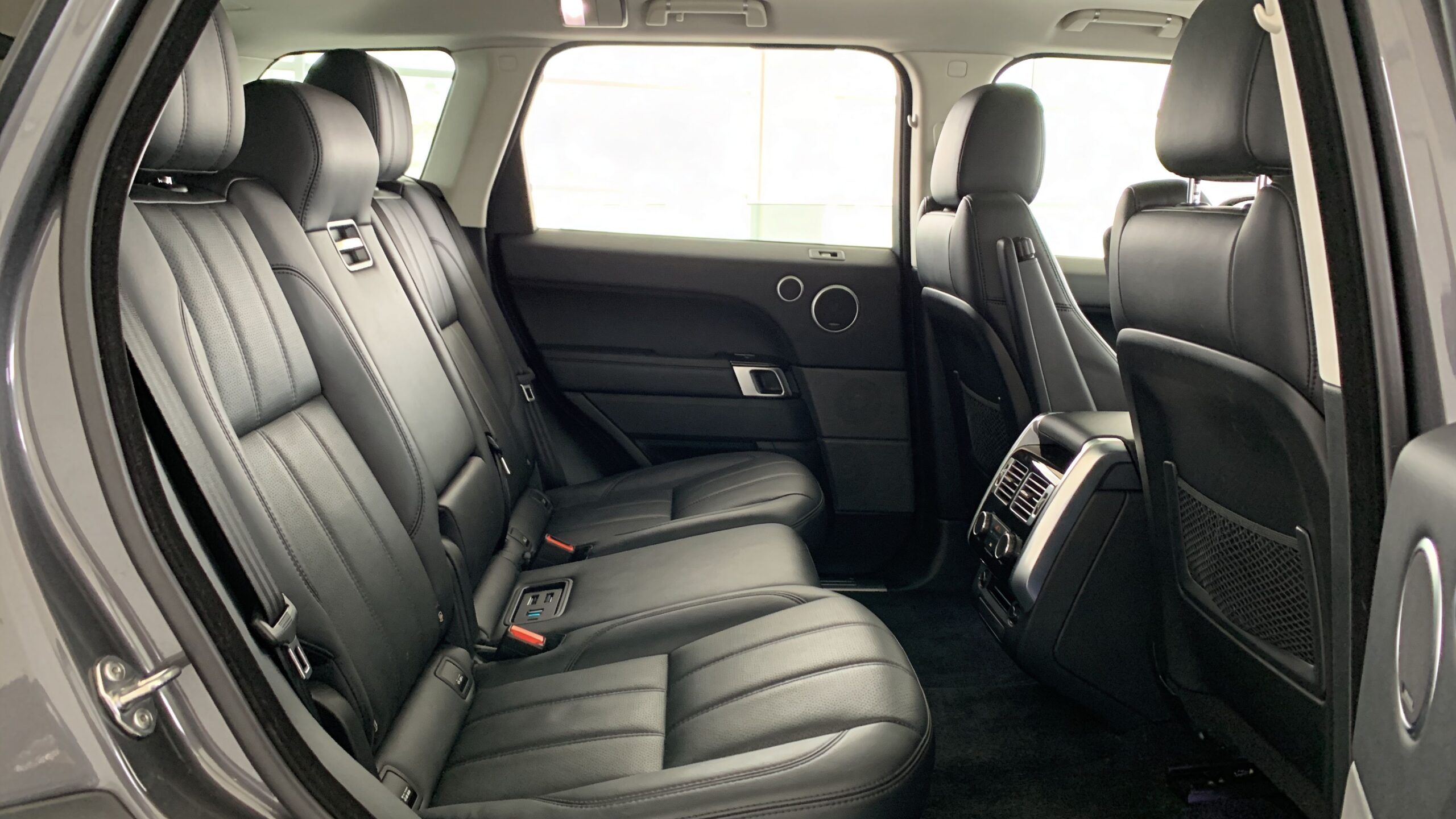 Rear passenger cabin of a luxury SUV featuring premium black leather seats and organized interior space.
